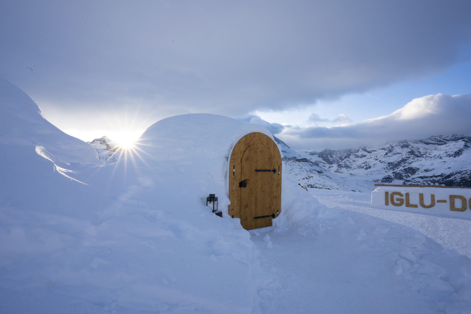 Snow domes of a mountain igloo village on an open snowfield.