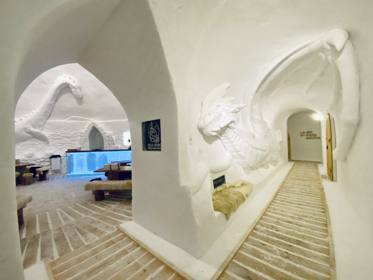 A snow lodge cut into a glacier below a rock summit.