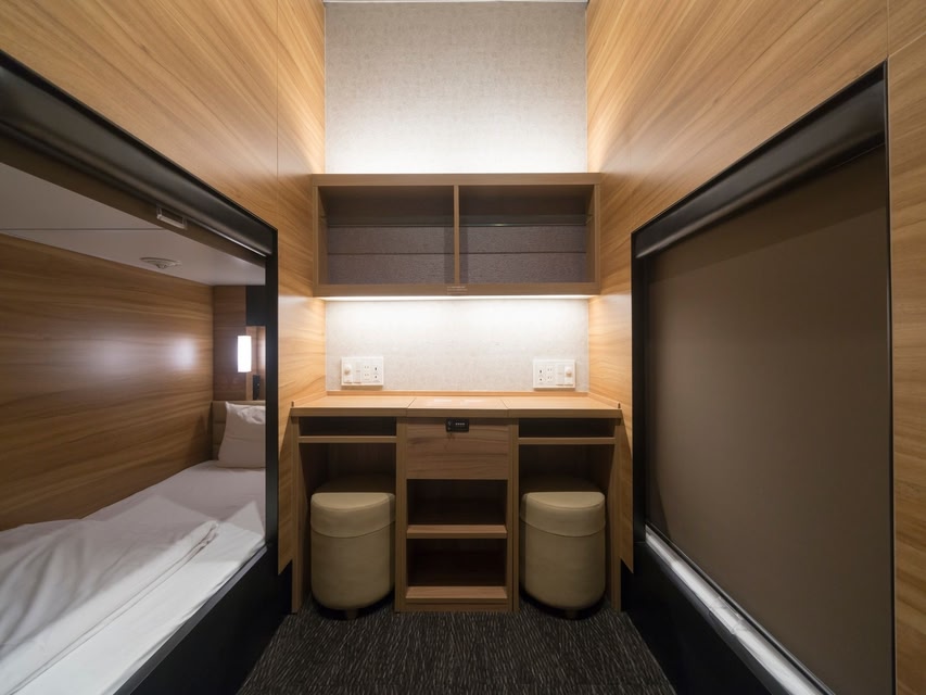 A corridor of cabin berths above a floor holding a shared bath.